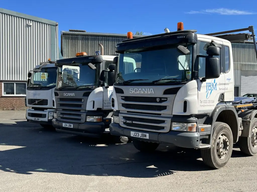 Photograph of a JBM Environmental Services trucks parked in a clean industrial yard. The truck is empty and prominently displays the JBM branding, emphasizing the company's professional fleet used for waste and recycling services