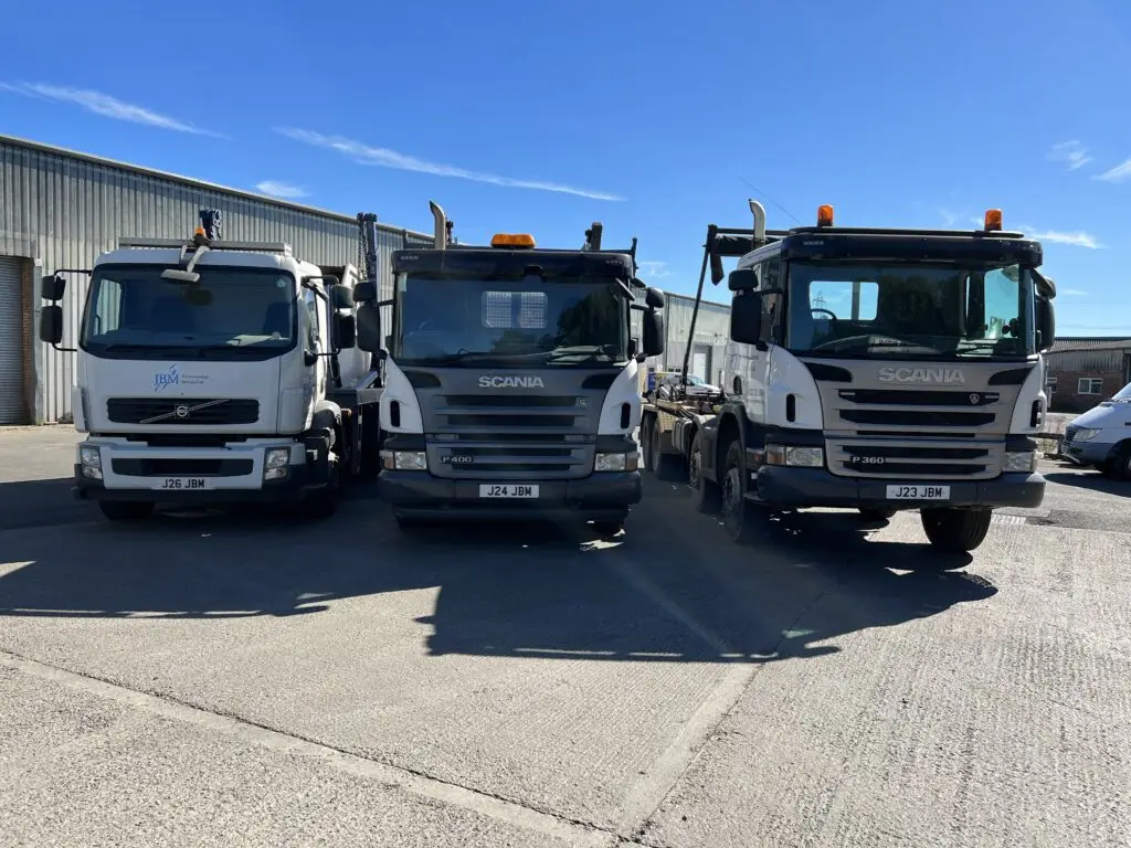 Photograph of a JBM Environmental Services truck parked in a clean industrial yard. The truck is empty and prominently displays the JBM branding, emphasizing the company's professional fleet used for waste and recycling services